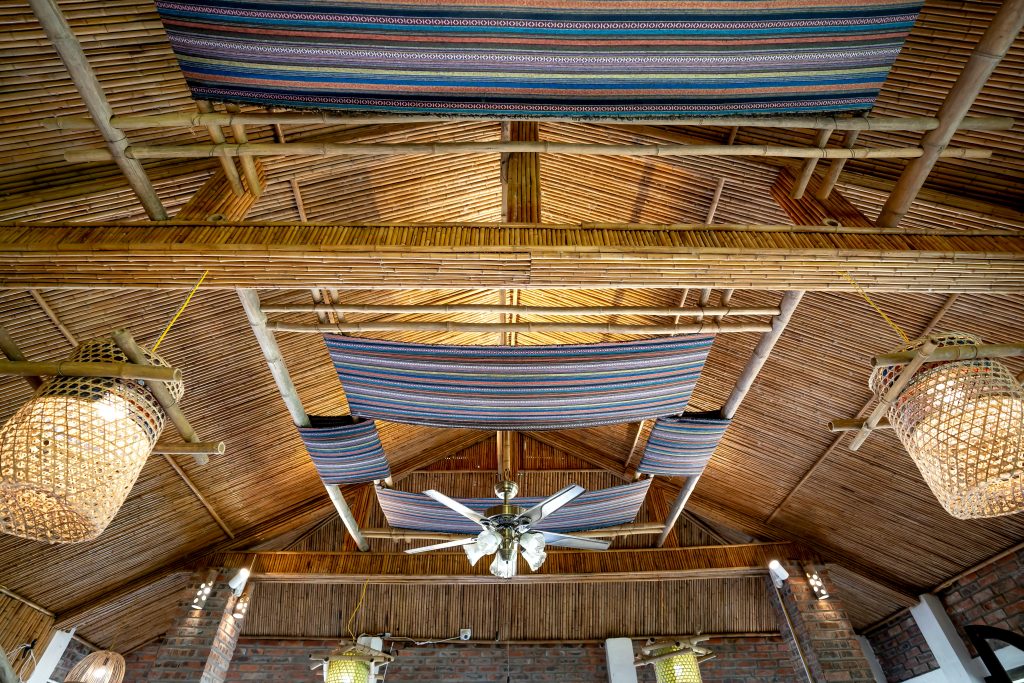 Interior view of a bamboo ceiling with hanging decor and wicker lighting fixtures.